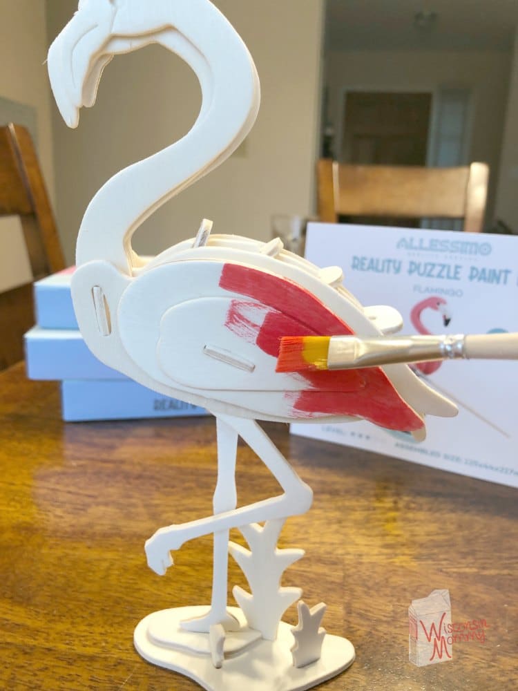paint brush with pink paint on wooden flamingo puzzle 
