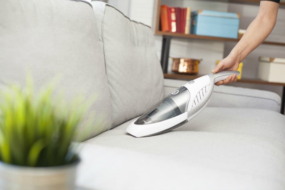 dust buster vacuuming white couch