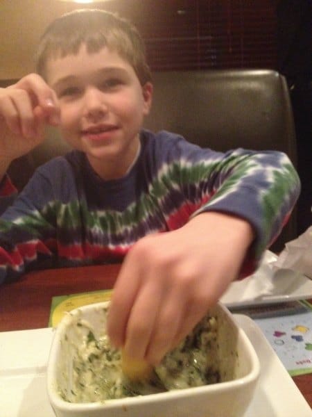 boy scooping spinach dip with chip