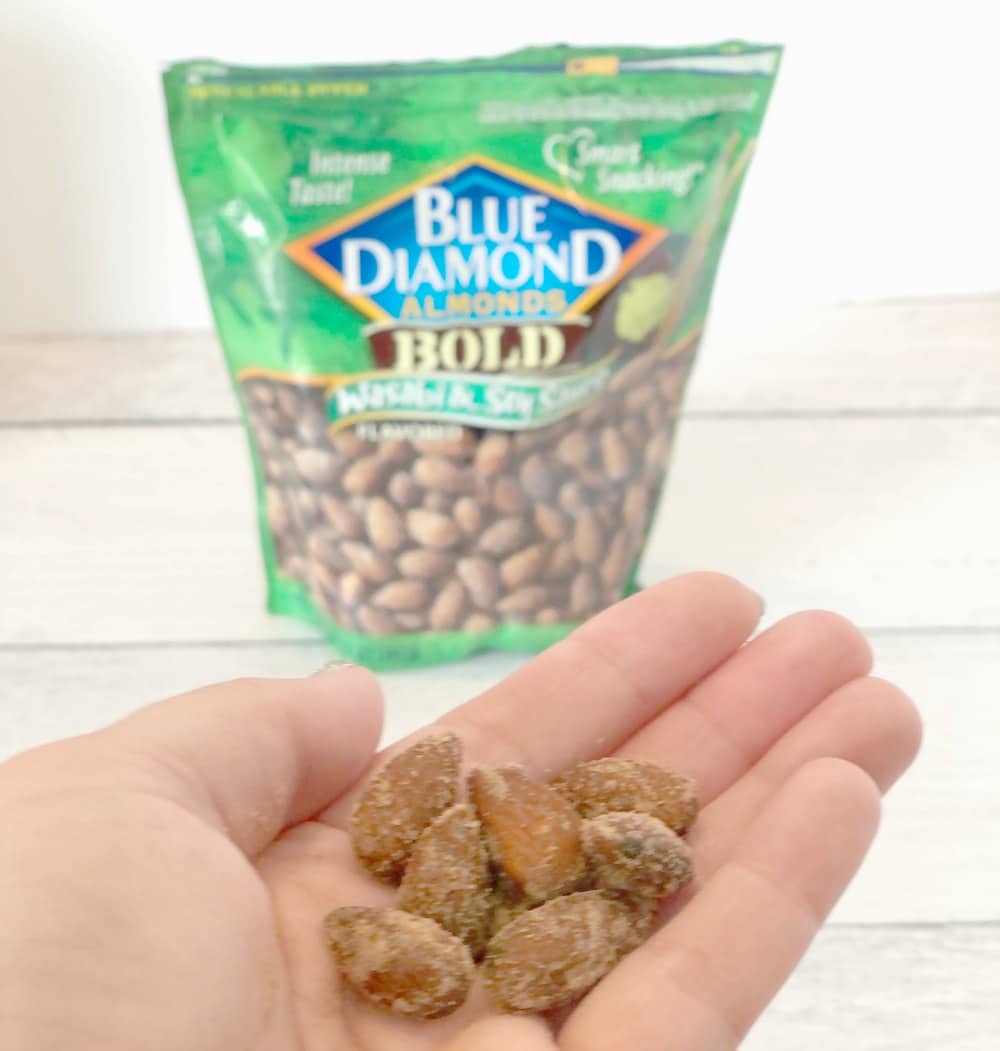 hand holding almonds in front of package