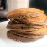 stack of chocolate pumpkin pancakes with syrup and whipped cream