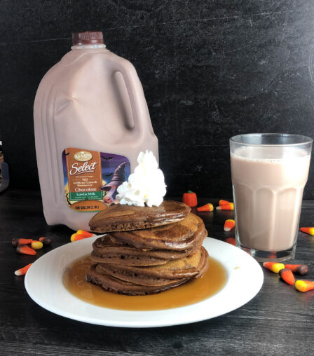 stack of pancakes, gallon of chocolate milk and a glass of milk