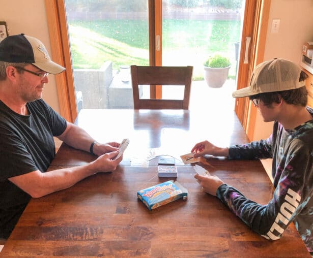 father and son playing cards at a wooden kitchen table