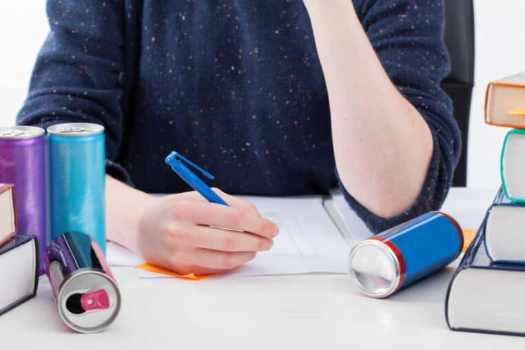 overworked student with empty energy drink cans