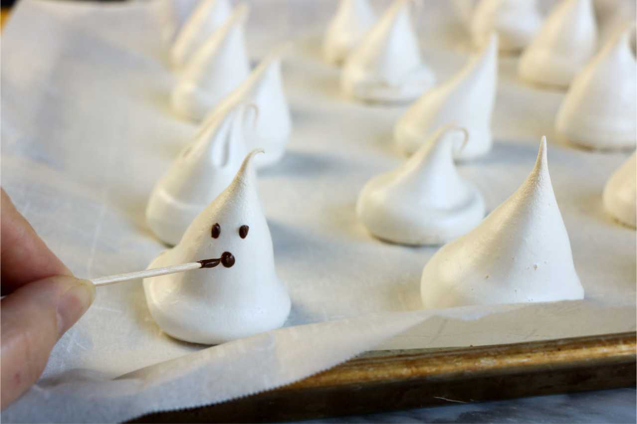 toothpick painting faces on meringue ghosts