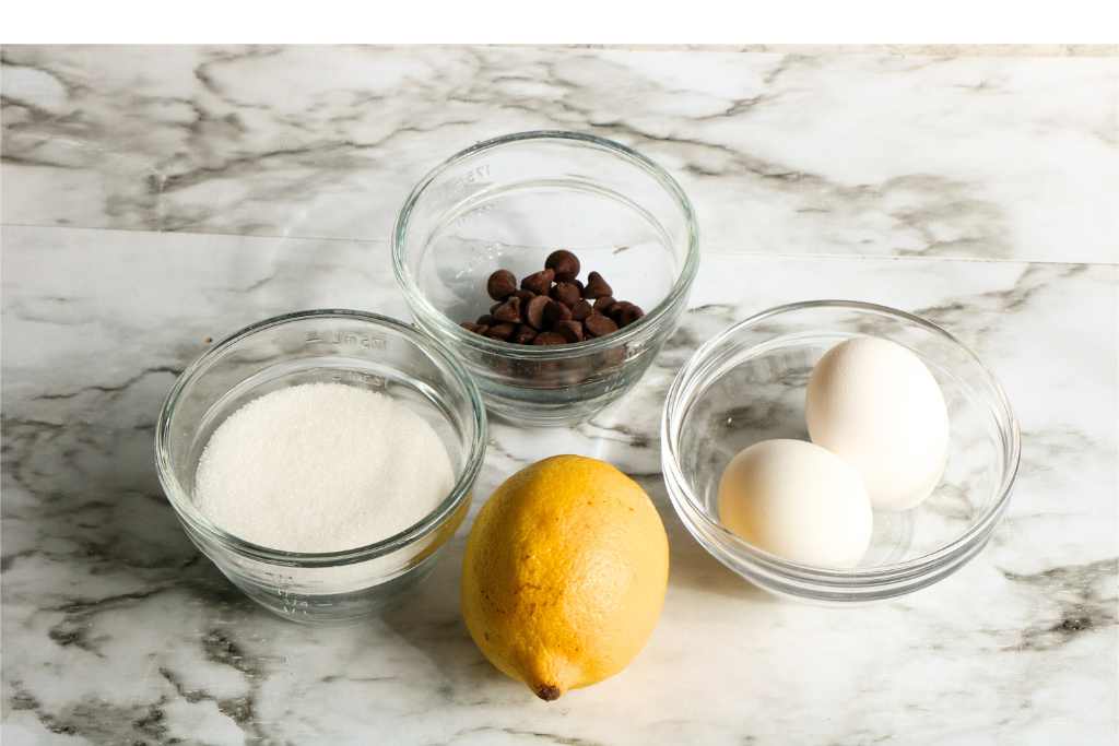 sugar, lemon, eggs and chocolate chips in bowls