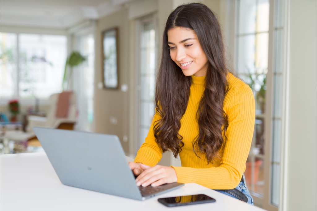 Smiling woman typing on laptop in a home