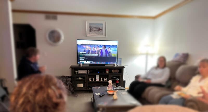 A group of people sitting in a living room watching The Chosen on TV