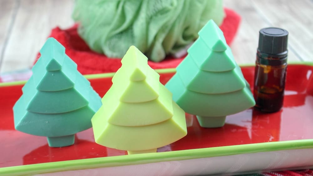 three green soaps shaped like pine trees on a red dish