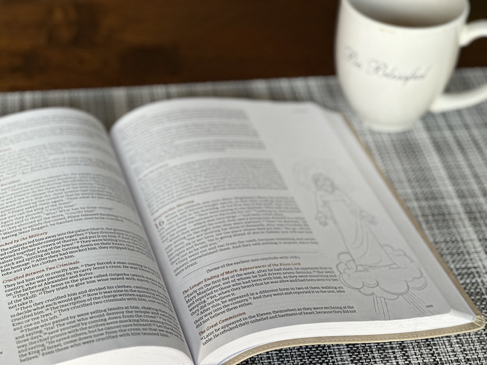 open bible on a table next to a cup of coffee